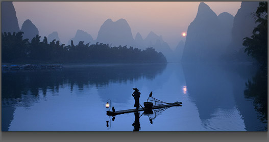 Image of a Man standing on a Boat at Sunset